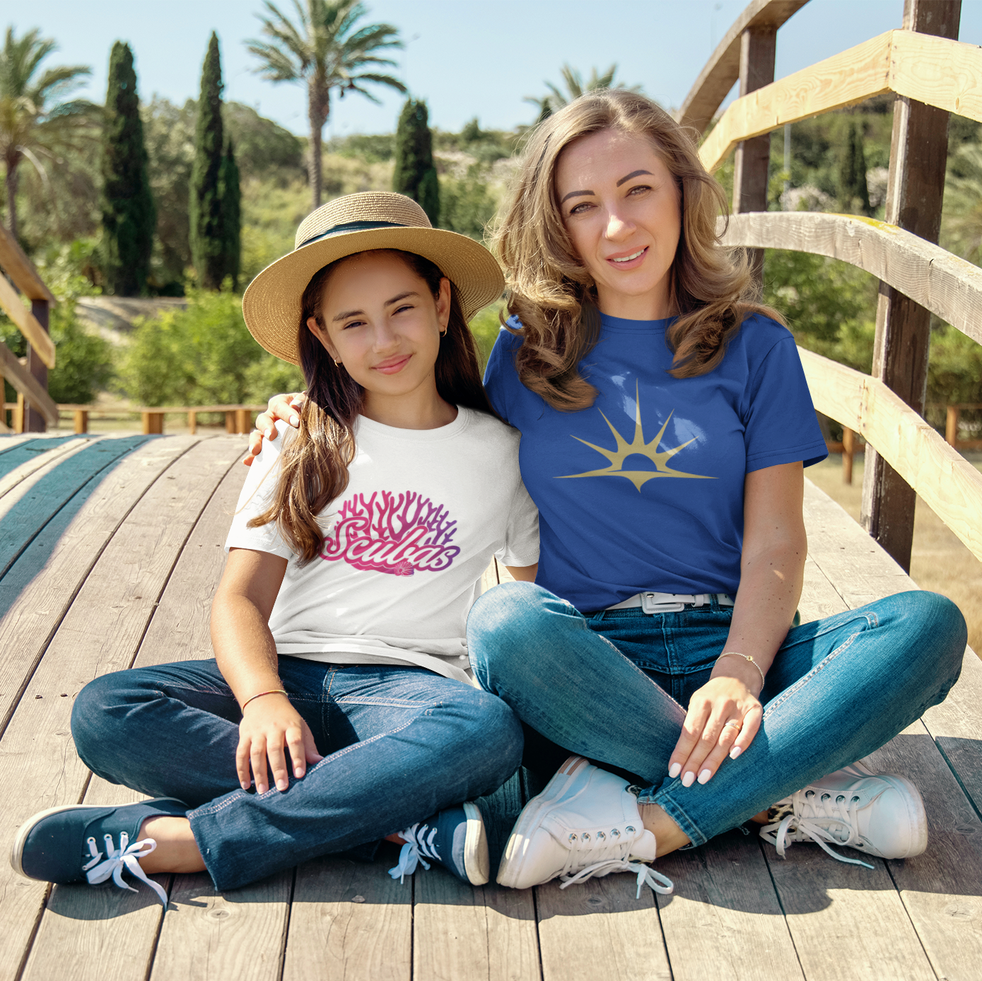 Two women sitting on a wooden bridge with palm trees in the background